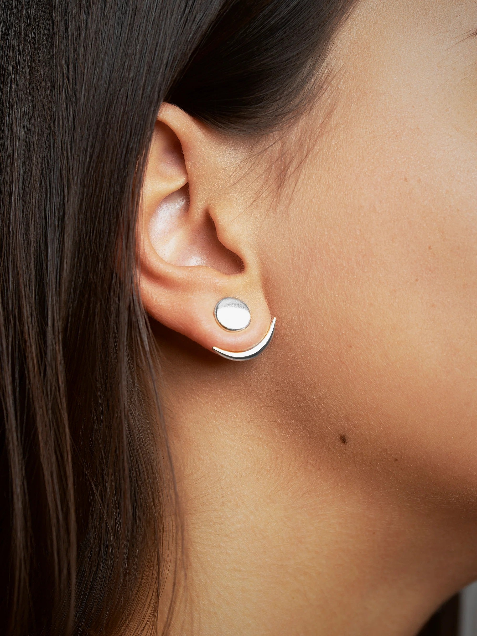 Sterling silver shiny ear jackets worn by a model with tied-back hair.