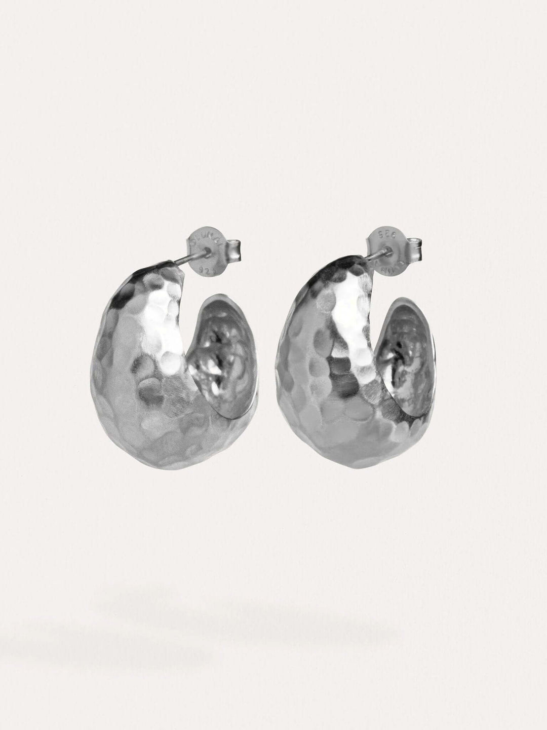 Silver hammered hoop earrings on a white background