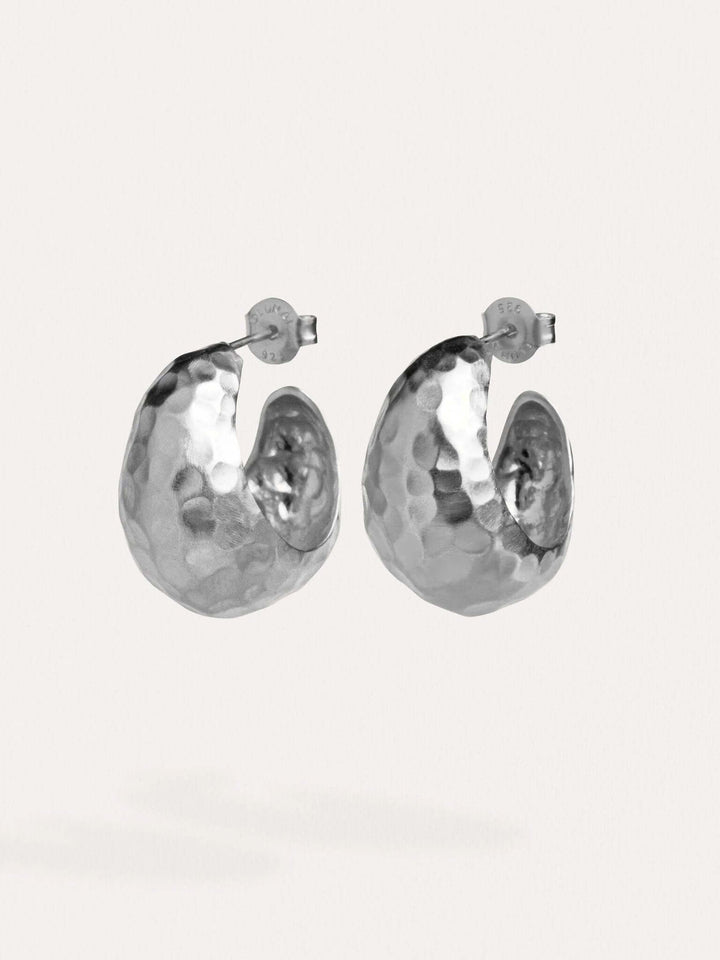 Silver hammered hoop earrings on a white background