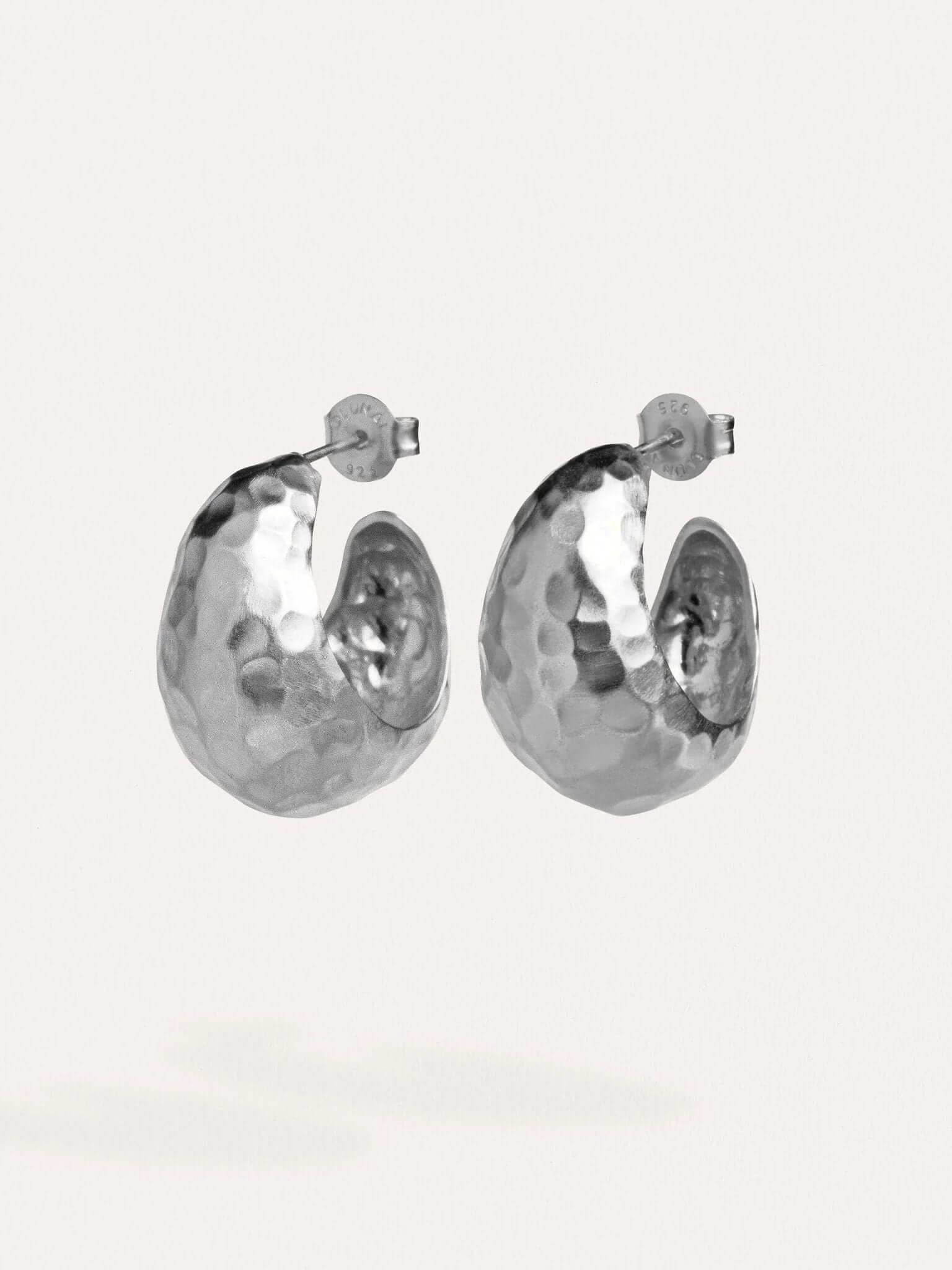 Silver hammered hoop earrings on a white background