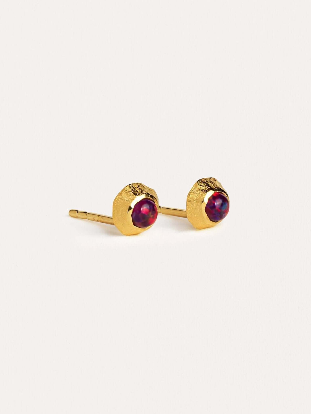 Delicate gold earrings with contrasting red gemstones.