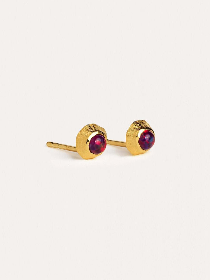 Delicate gold earrings with contrasting red gemstones.