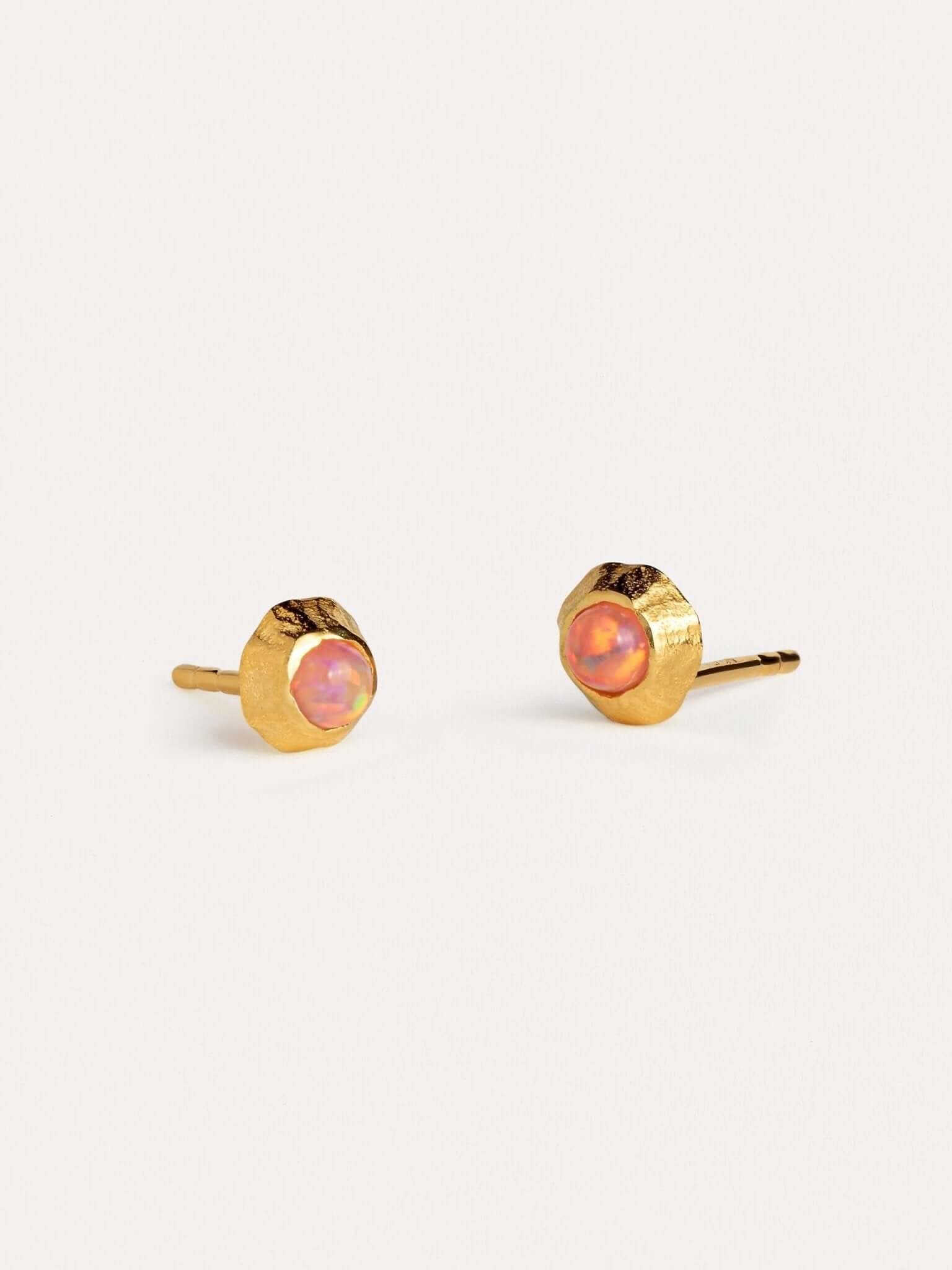 Gold stud earrings with vibrant orange gemstones in a bezel setting.