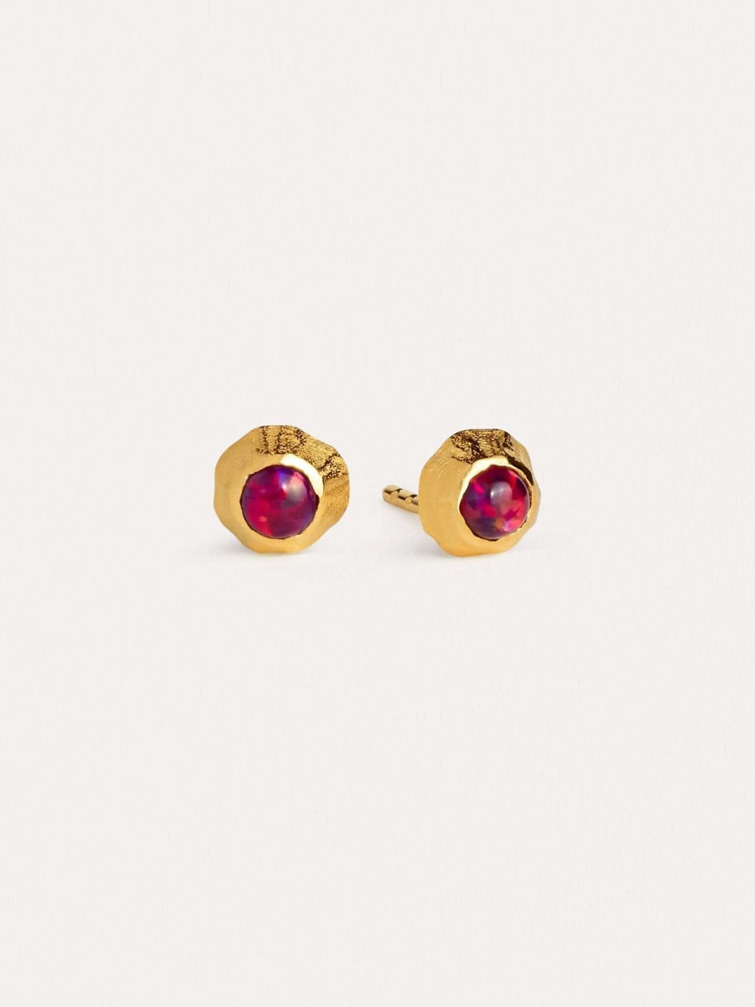 Dainty gold earrings with deep red garnet gemstones in a bezel setting.