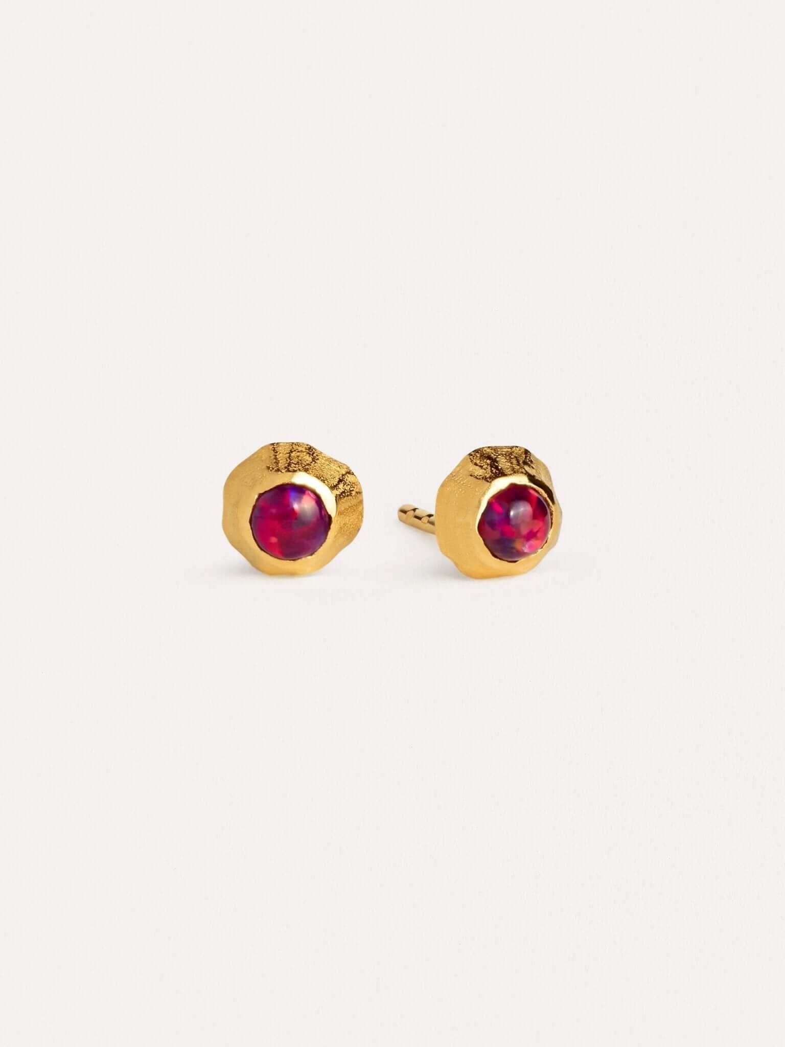 Dainty gold earrings with deep red garnet gemstones in a bezel setting.