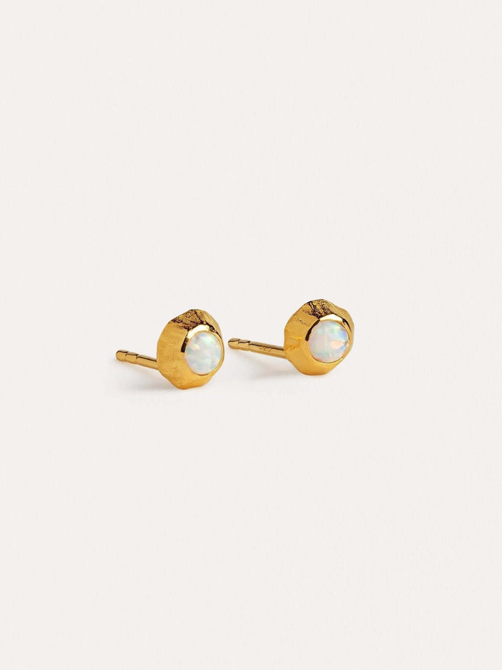 Minimalist gold bar earrings with bezel-set gemstones on neutral background.