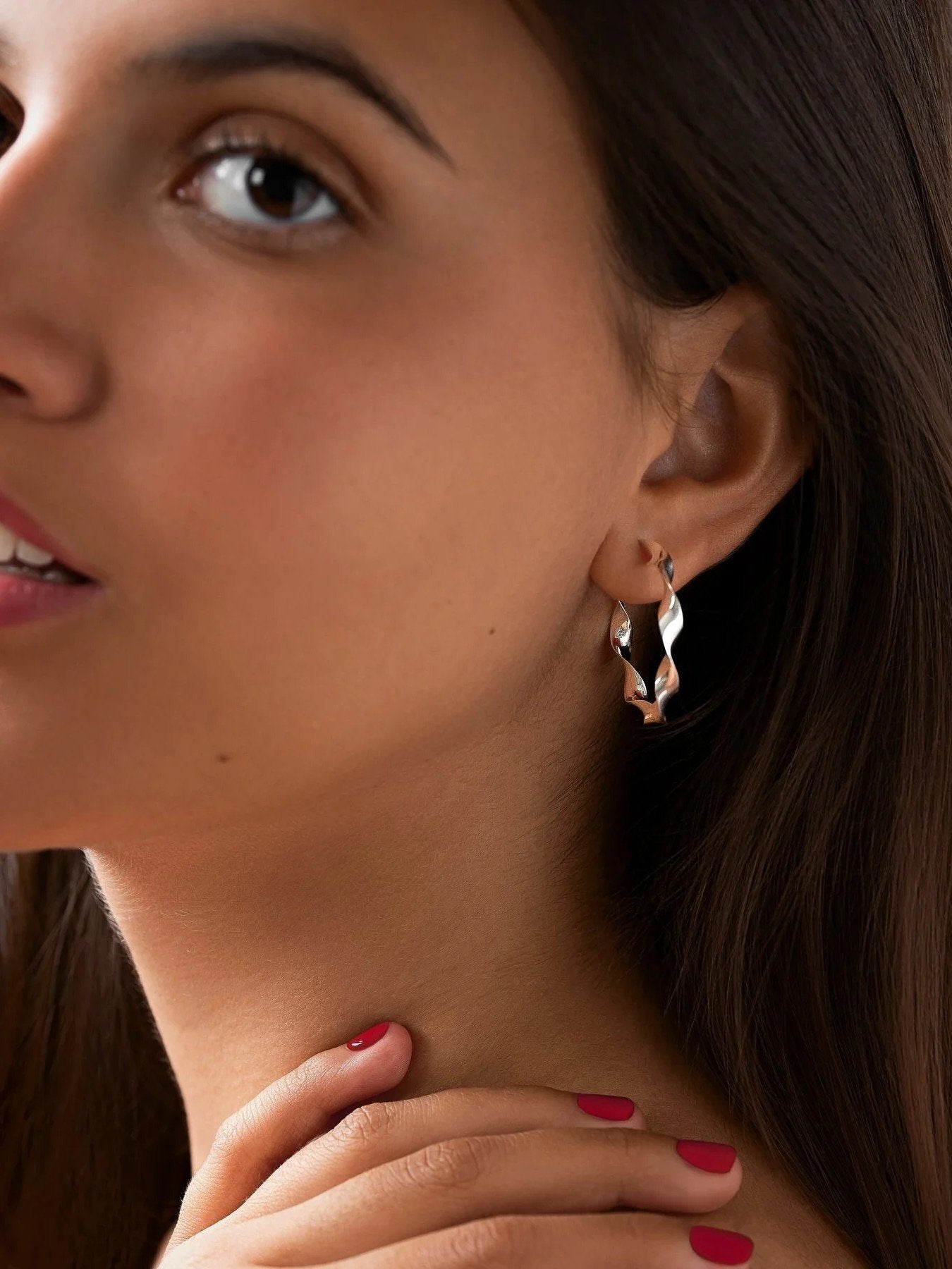 "Model wearing Gene Twisted Hoop Earrings in silver, front view with soft lighting"