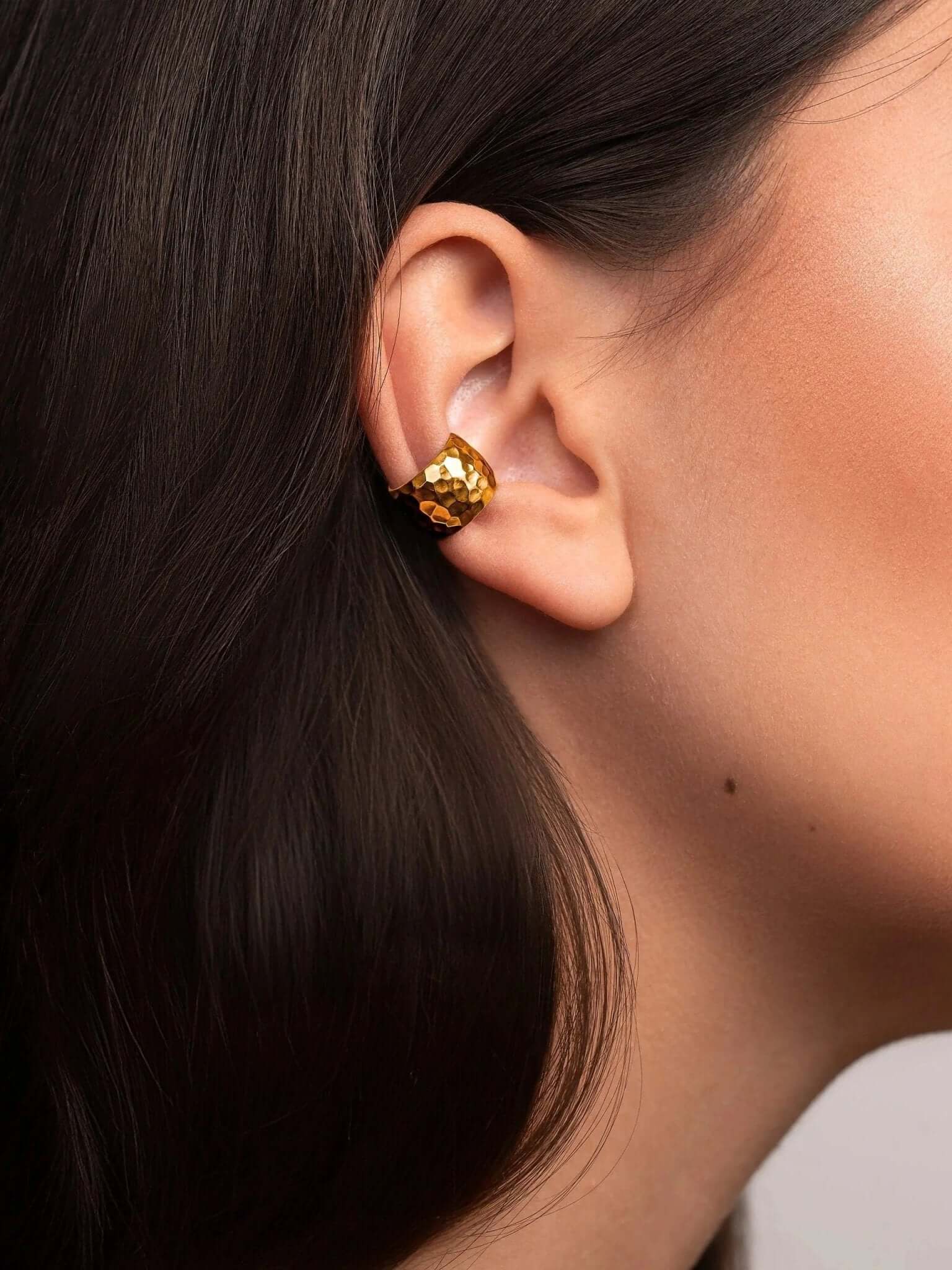 Close-up of the handcrafted gold conch cuff earring with hammered finish and elegant texture.