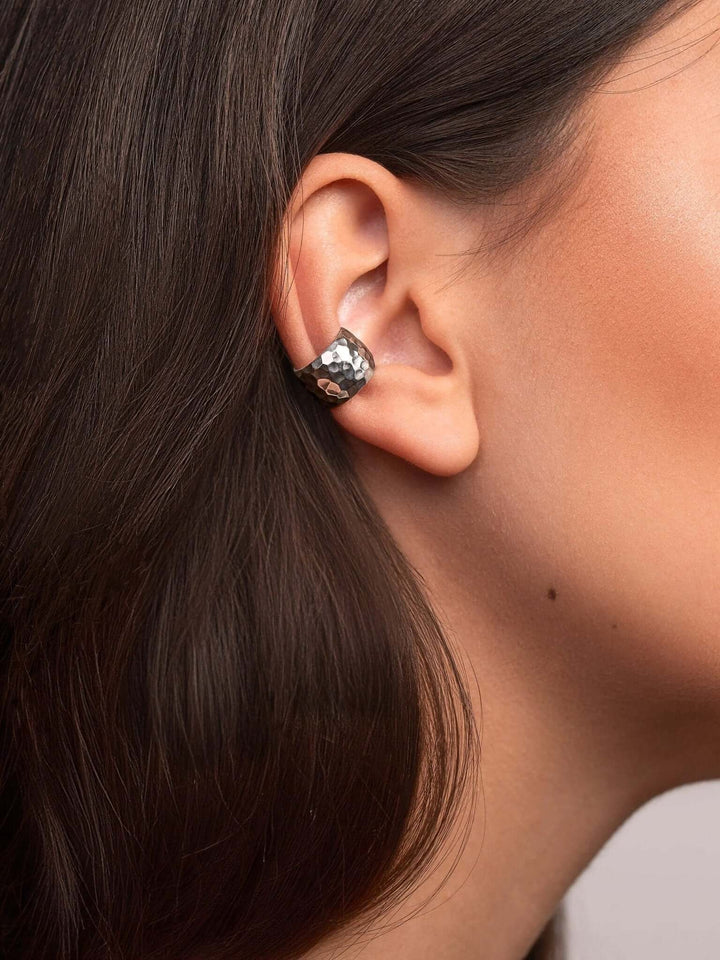 Silver conch cuff earring catching the light, highlighting its sustainable, artisanal craftsmanship.