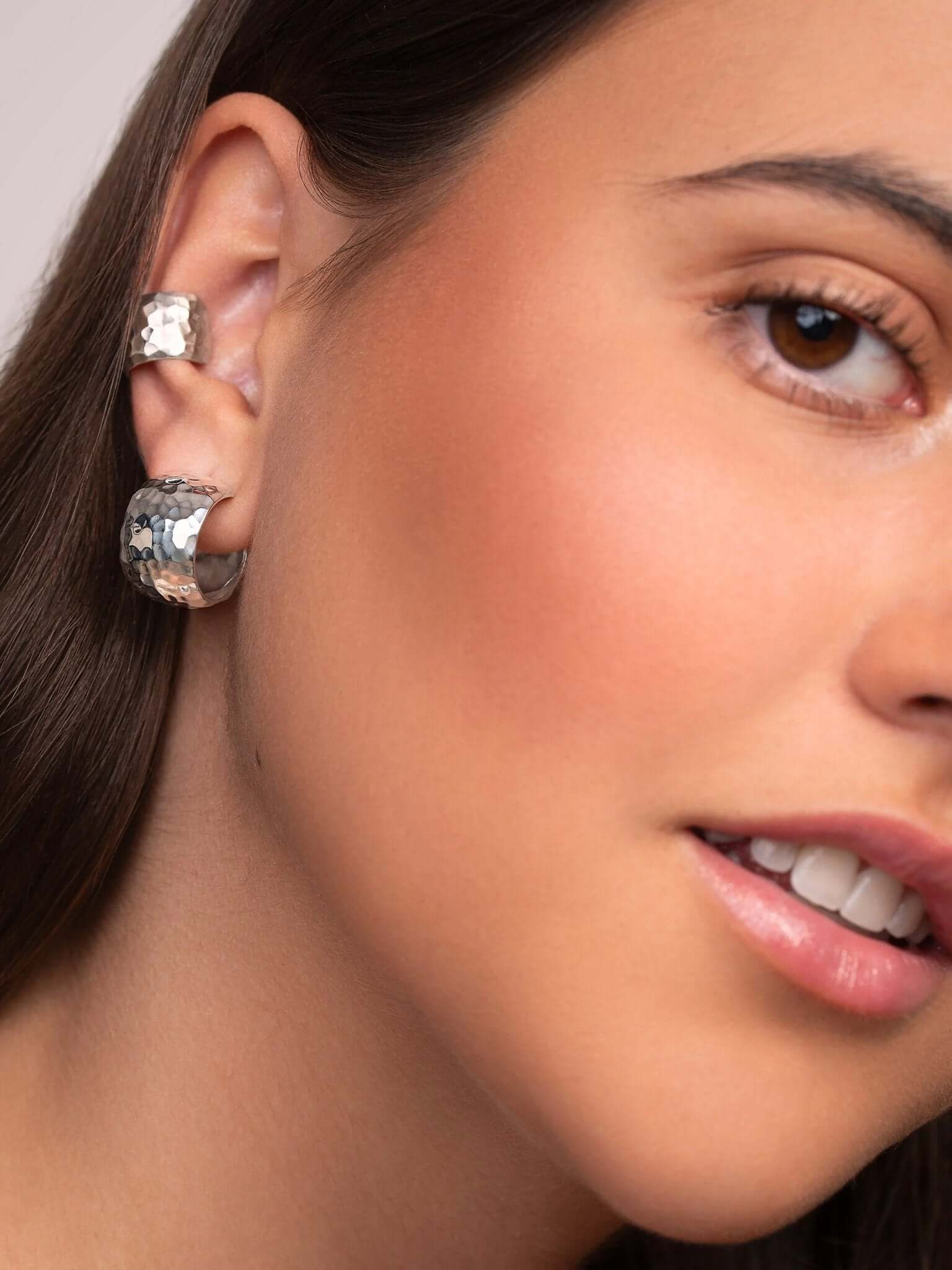 Close-up of the handmade silver conch cuff earring, showing the hammered detail and smooth curves.