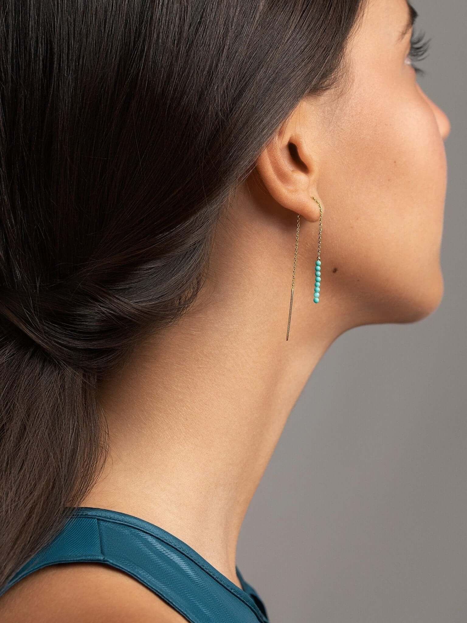 Long gemstone threader earrings in gold, worn elegantly with a minimalist look.