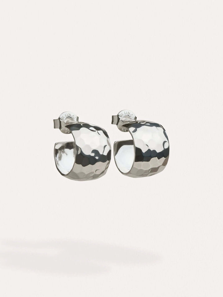 Sterling silver-plated hammered huggie hoops on a neutral background.