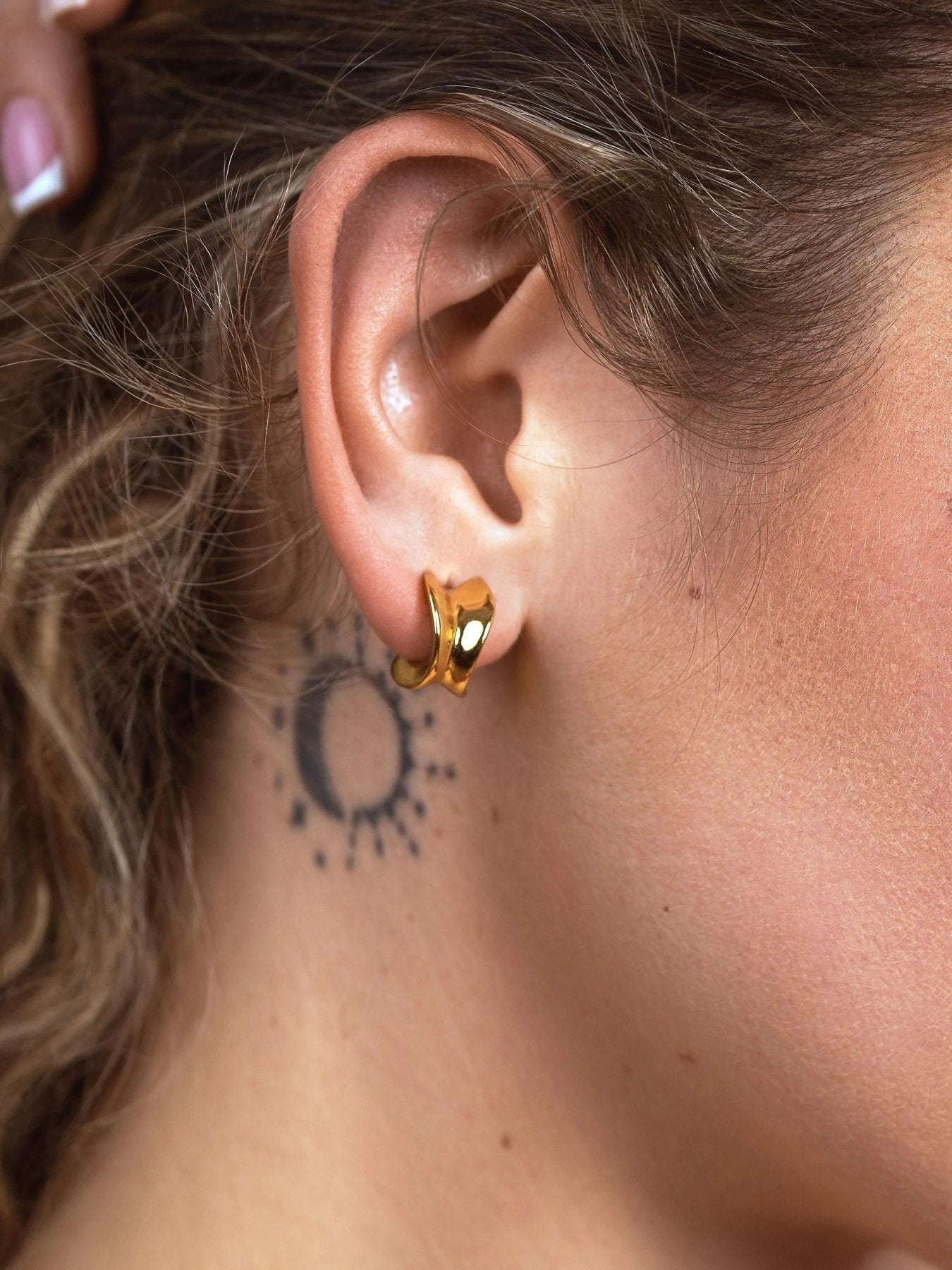 Model wearing small gold chunky hoop earrings, showing their petite 14 mm size on the ear.
