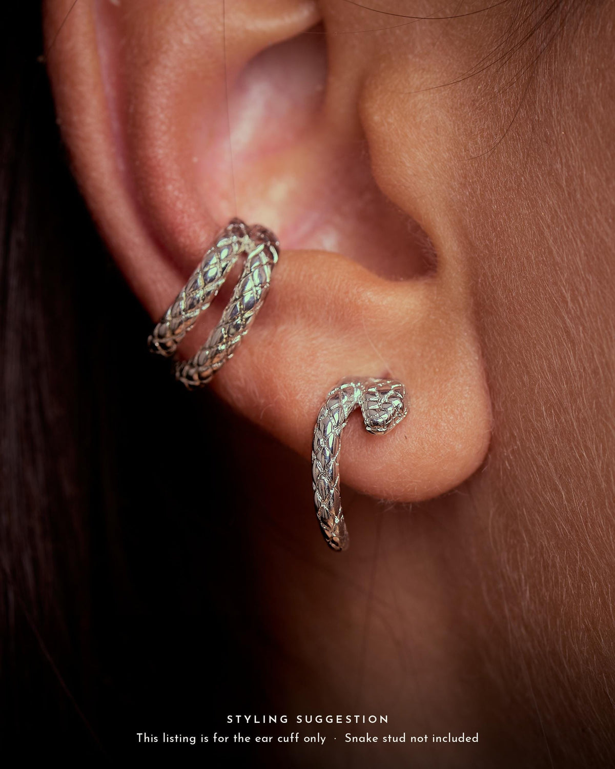 Ear wearing a sterling silver plated brass snake ear cuff on the conch, styled with a snake stud on the lobe. Ear cuff sold alone.