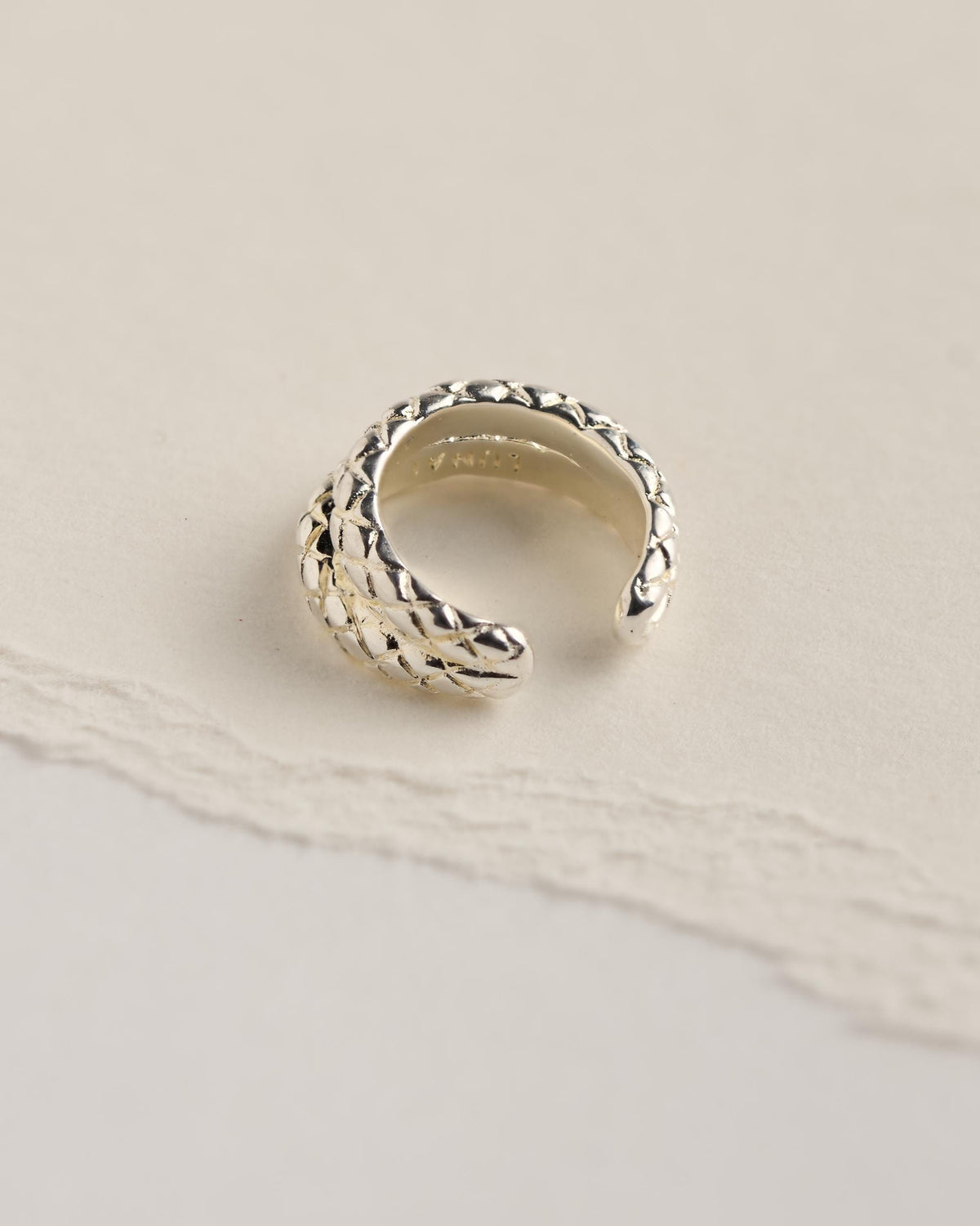 Sterling silver plated brass snake ear cuff viewed from above, showing the scale-textured snake heads and the LUNAI stamp inside.