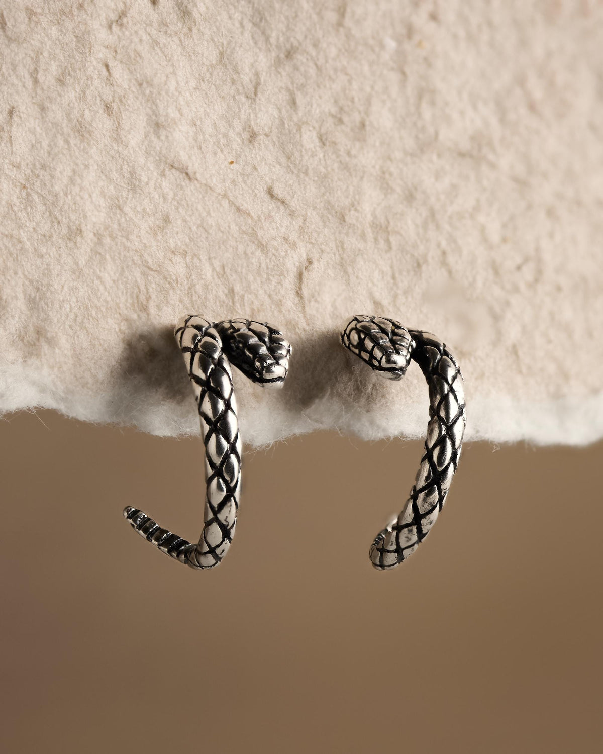 Pair of oxidized silver snake stud earrings with dark snakeskin texture