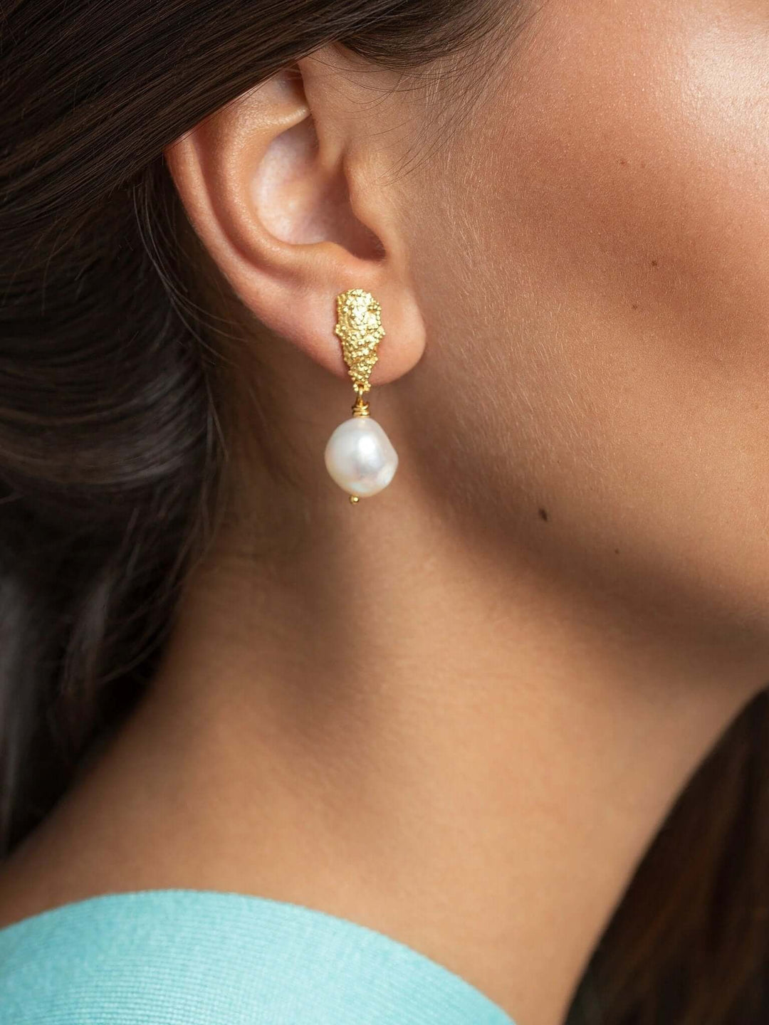 Close-up side view of model wearing baroque pearl earrings, highlighting pearl drop.
