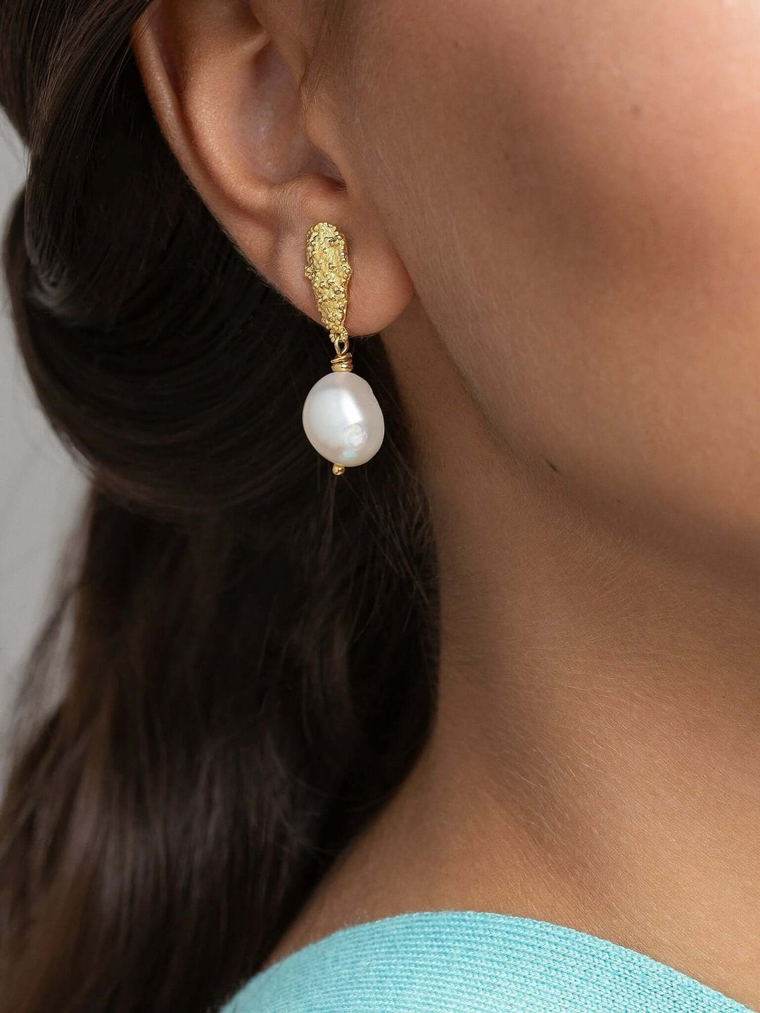 Baroque pearl earrings on model with low bun, showing the full earring length.