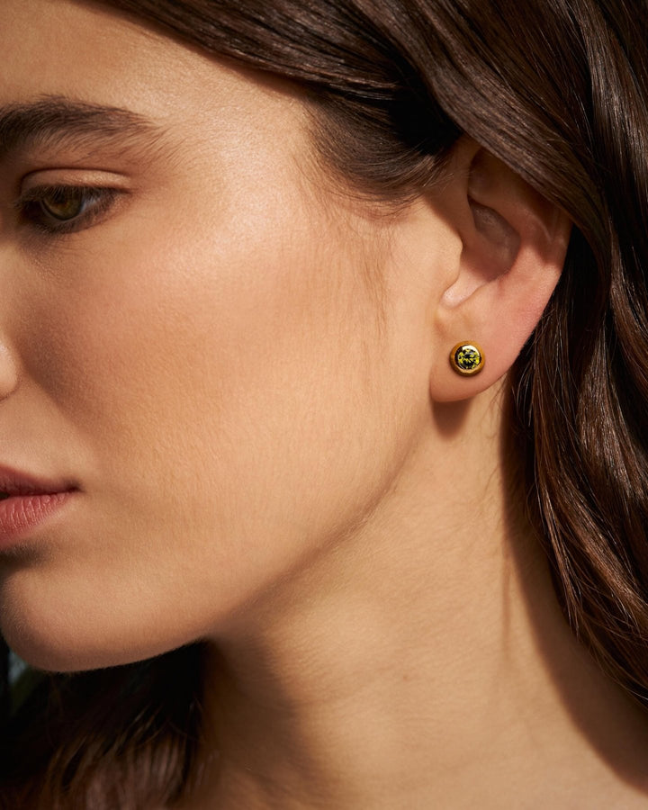 Woman wearing gold earrings with a green stone, side profile – model in profile highlighting the glow of the pink gemstone earring.