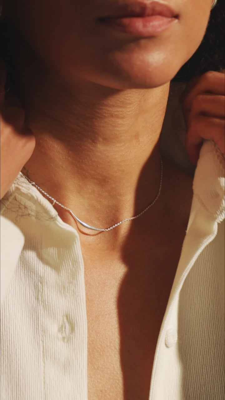 Model adjusting sterling silver 925 hoop earring in slow, graceful motion — close-up video portrait.