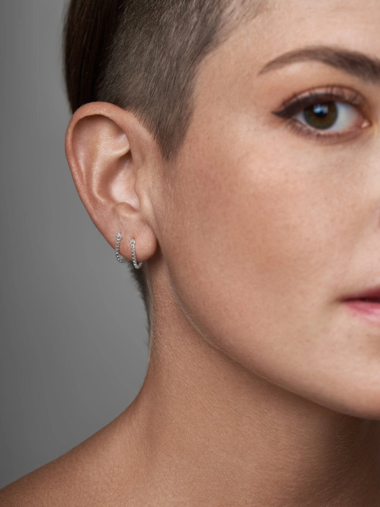 Close-up of gold threader earring on shaved side hairstyle