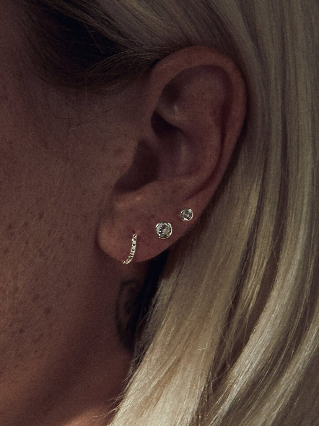 Gold chain earring worn by blonde model, cartilage placement detail