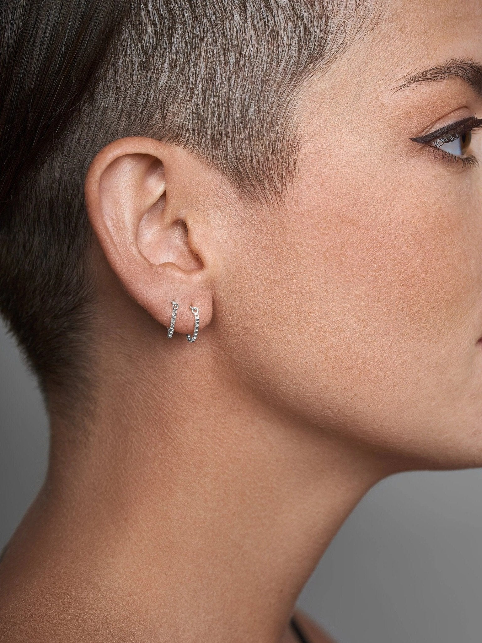 Gold chain threader earring on short-haired model, side profile view