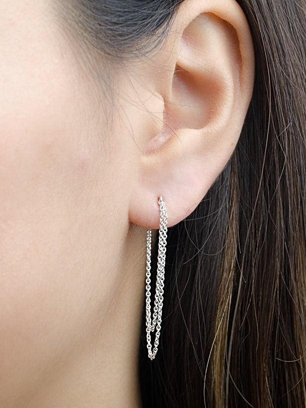 Silver double chain earrings worn on ear, close-up