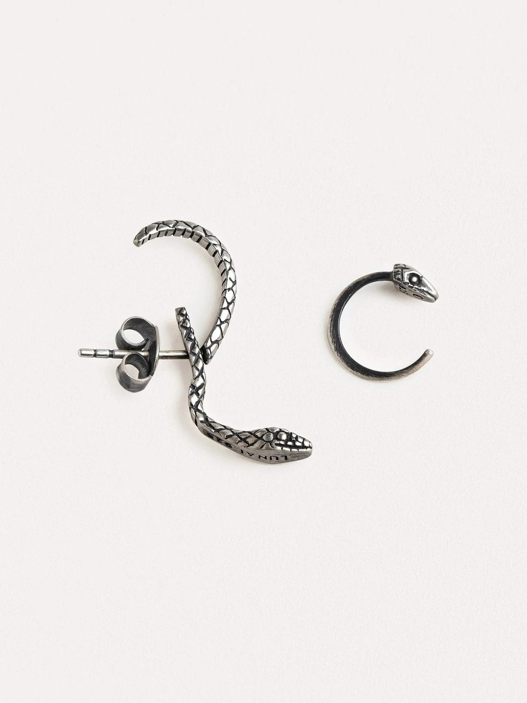 Close-up of an oxidized silver snake hoop earring on an ear, highlighting its textured details and unique shape.