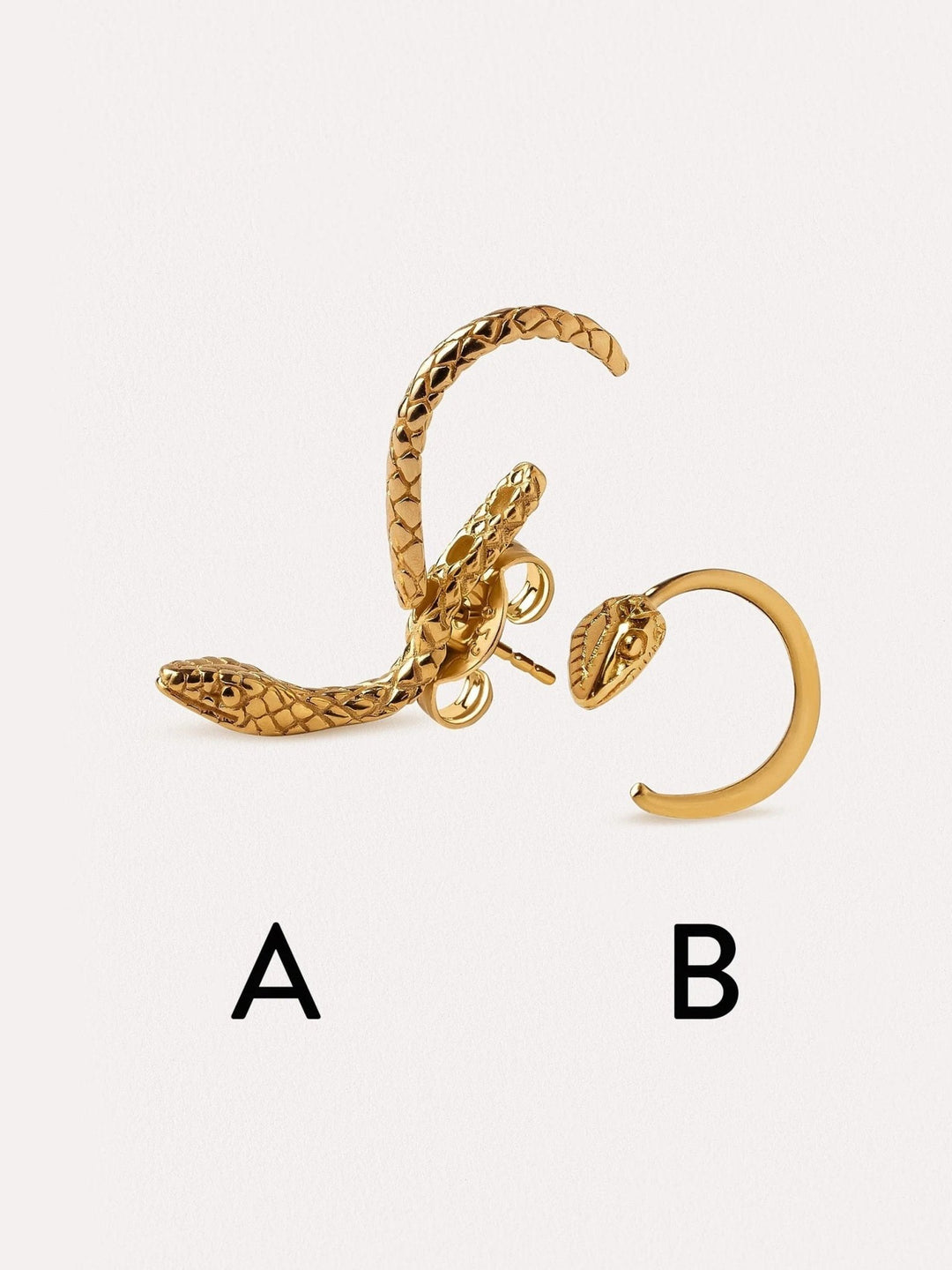 Set of two snake hoop earrings in gold, artistically arranged on a neutral surface.