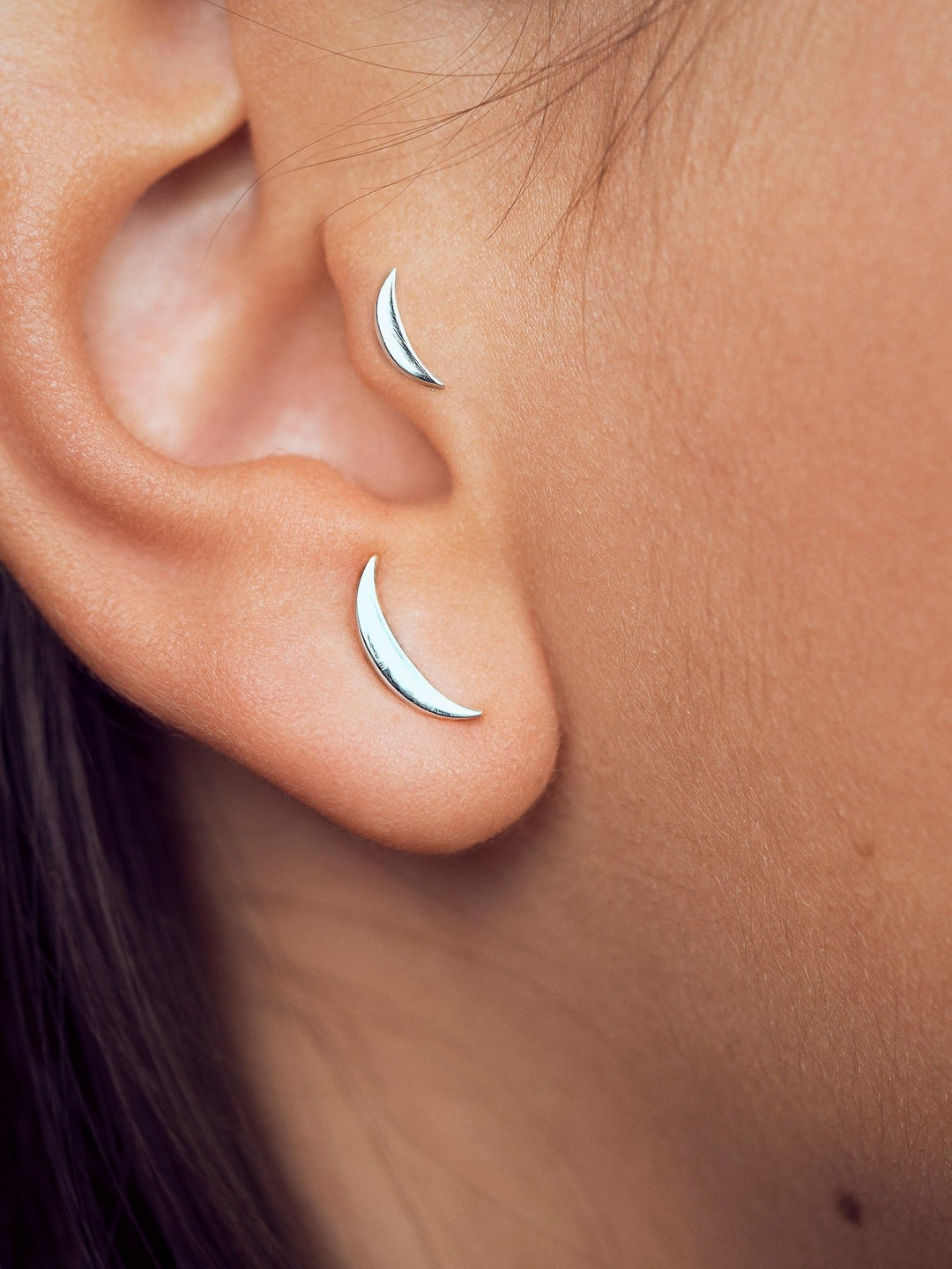 Close-up of sterling silver cartilage piercing with flat back, worn on the helix.