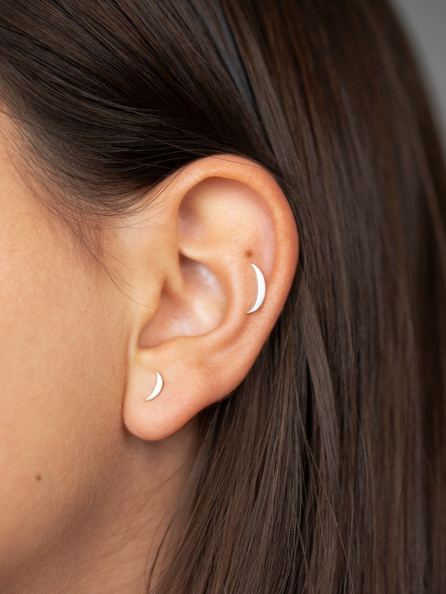 Model wearing multiple cartilage piercings on the ear, showcasing versatile styling.