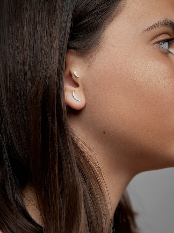 Profile view of woman wearing the Athina piercing, highlighting the gold detail on her ear.