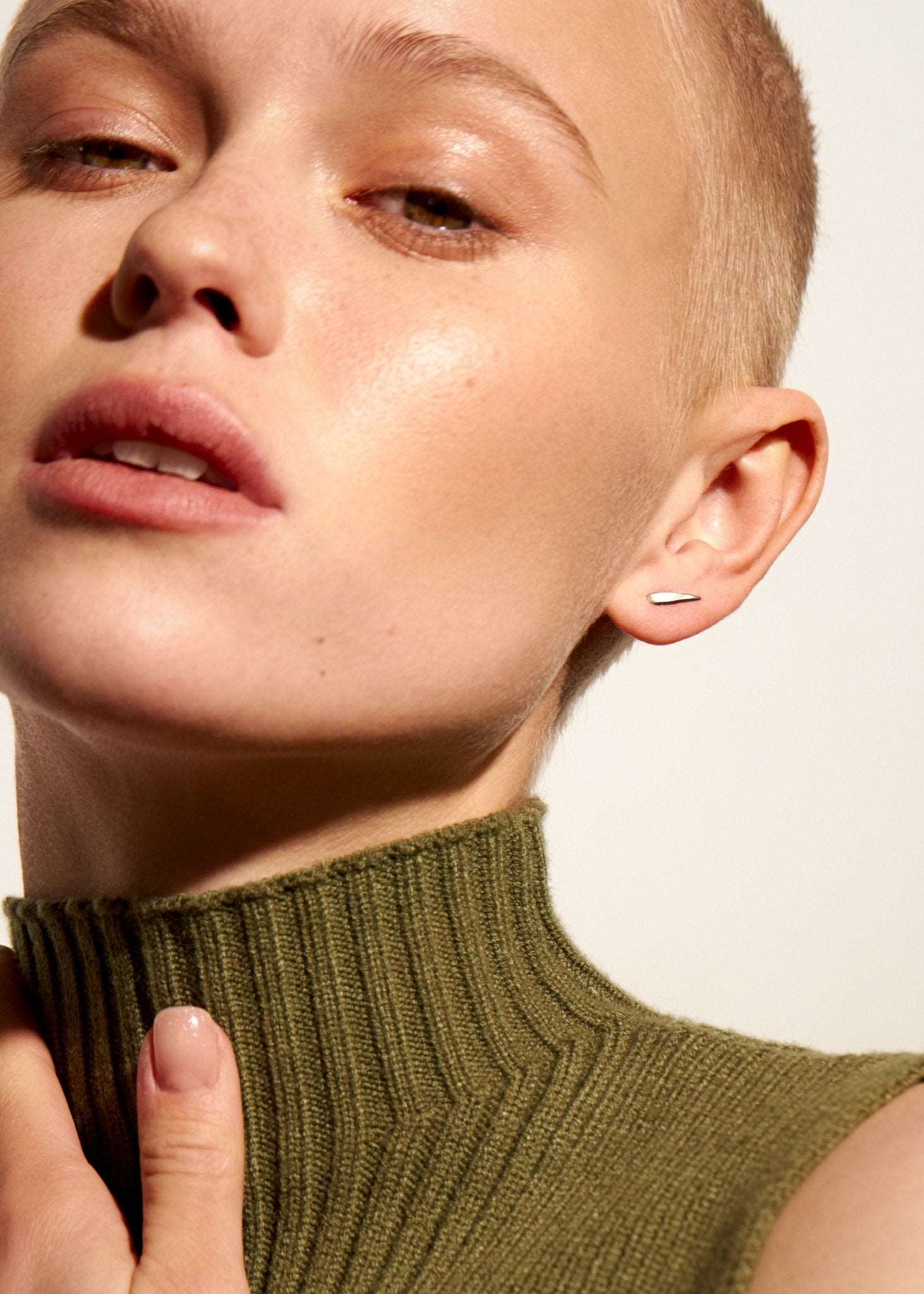 "Model wearing Aura Dainty Tusk Earrings in silver with soft lighting"