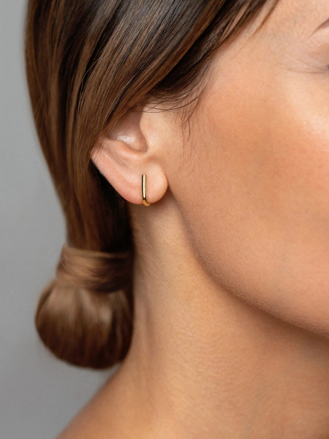 Sita gold bar earring worn — clean, polished finish styled with hair up.