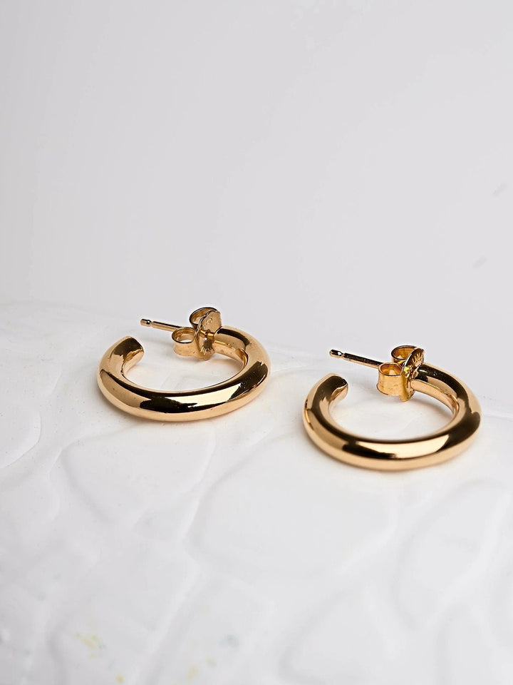 Pair of Birte open hoop earrings in sterling silver and 24K gold plated — minimalist medium size design on white background.