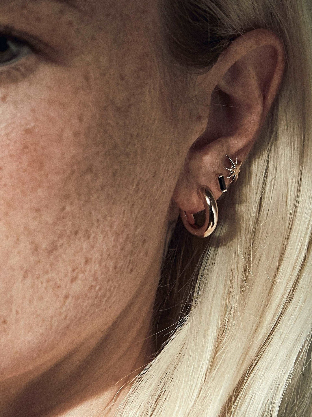 Close-up of gold Birte hoop earring worn — elegant everyday statement look.