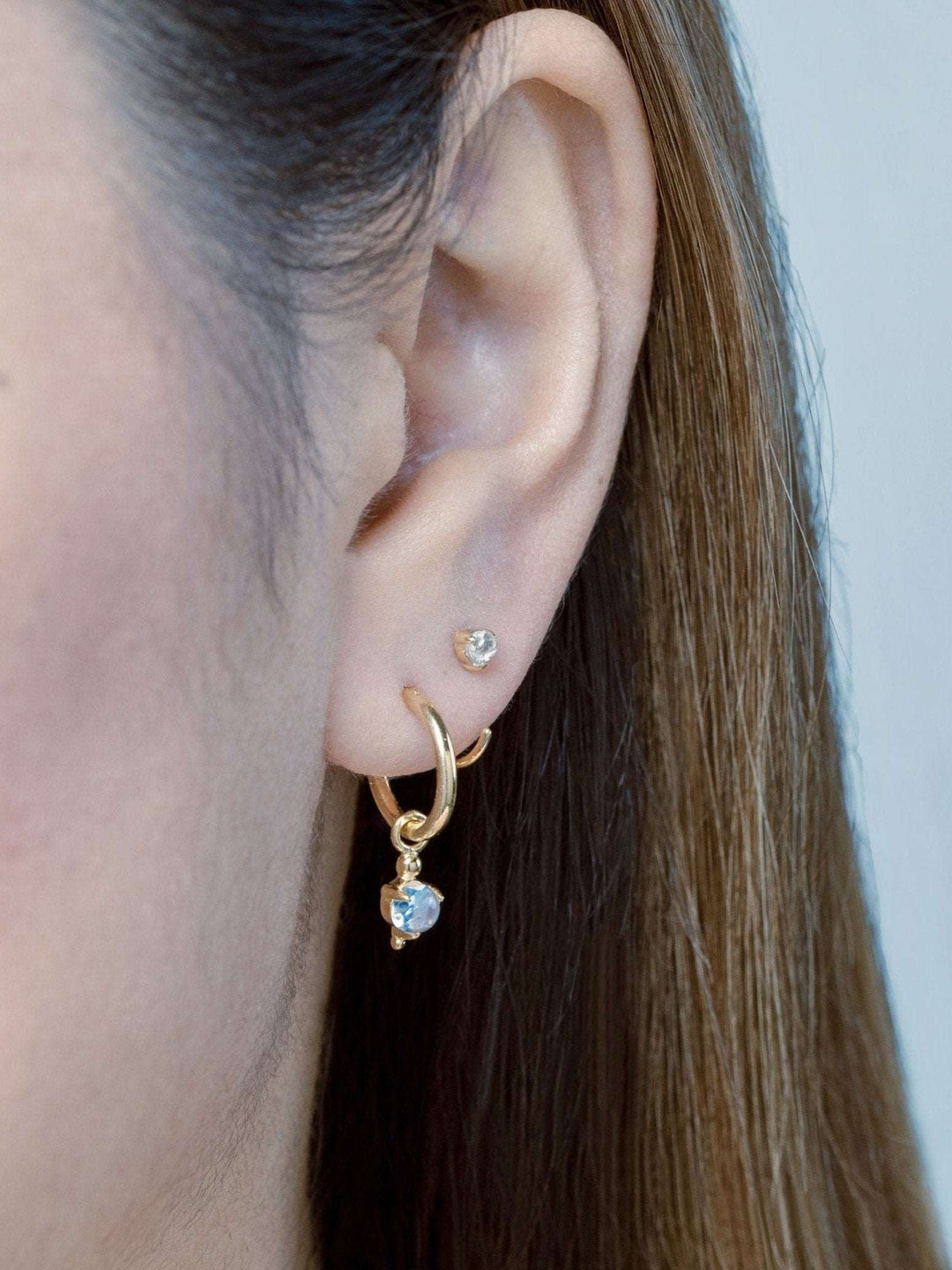 Close-up of model wearing gold hoop earrings with natural moonstone