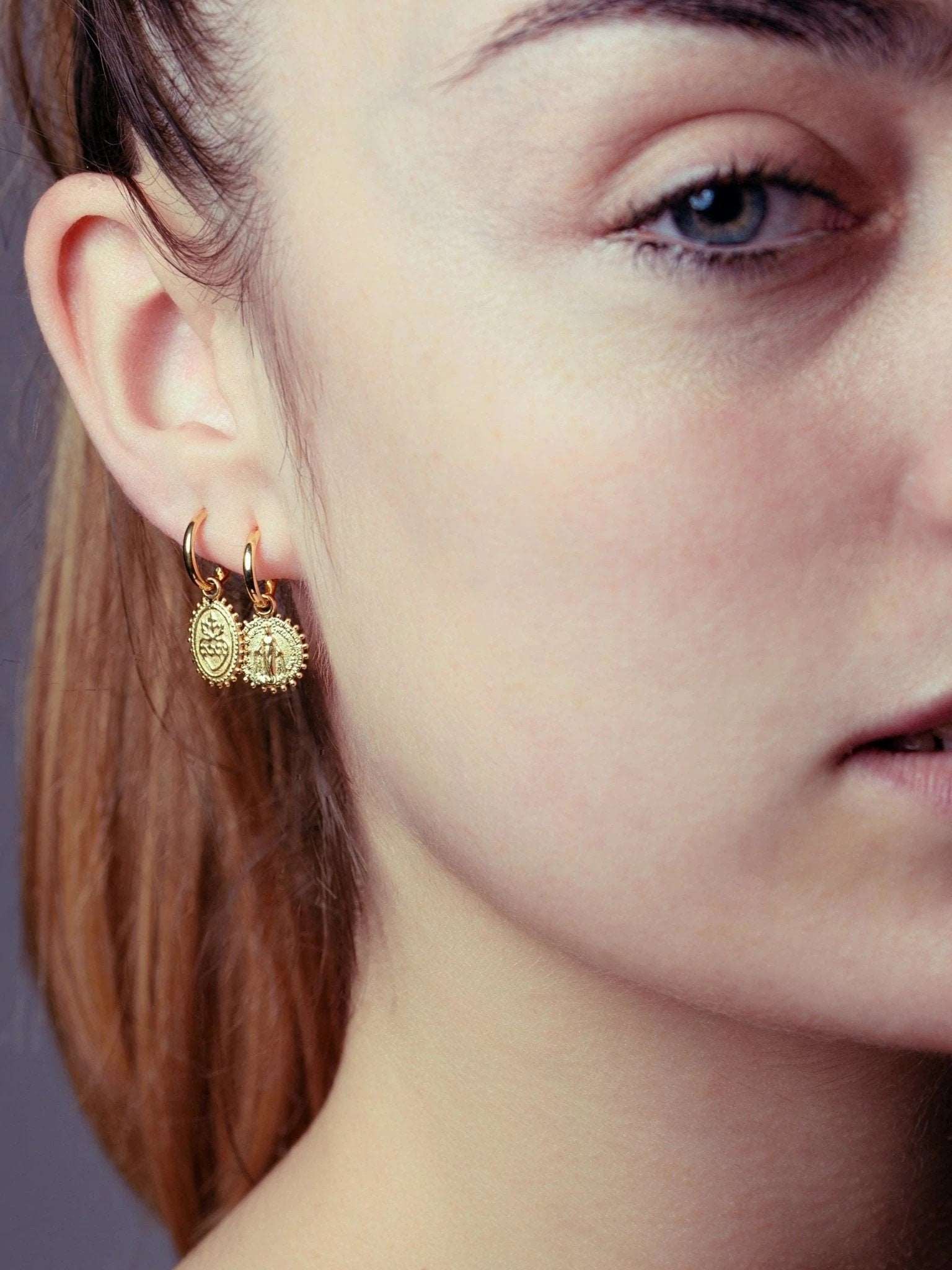 Gold plated Codi Mini Hoops on model – soft light and intimate portrait highlighting the charm’s spiritual detail.