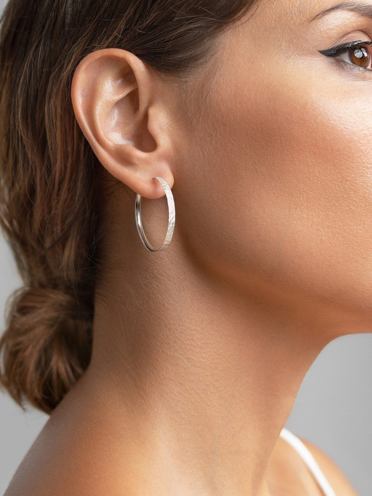 Model wearing 925 sterling silver matte hammered hoop earring – handmade and sustainable.