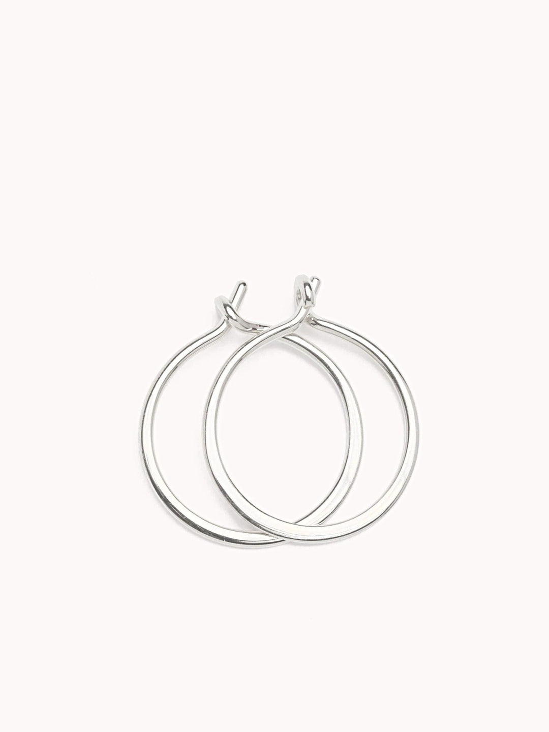 Double sterling silver hoop earrings with an intertwined modern design on a soft pink background