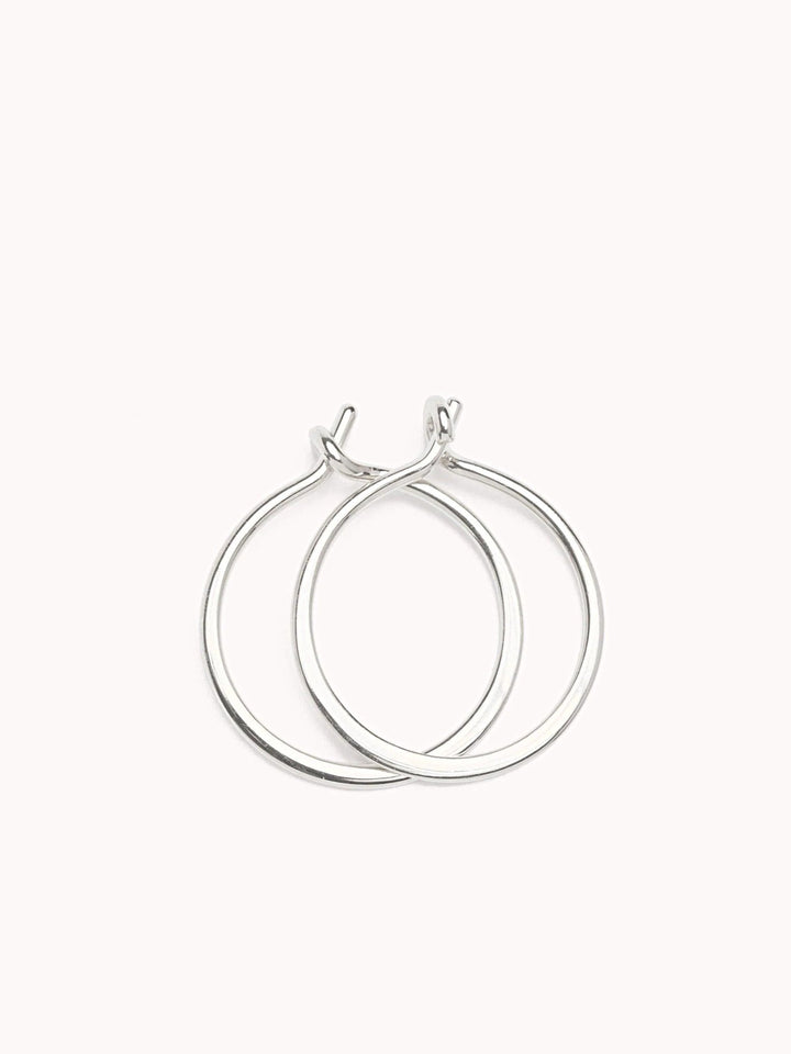 Double sterling silver hoop earrings with an intertwined modern design on a soft pink background