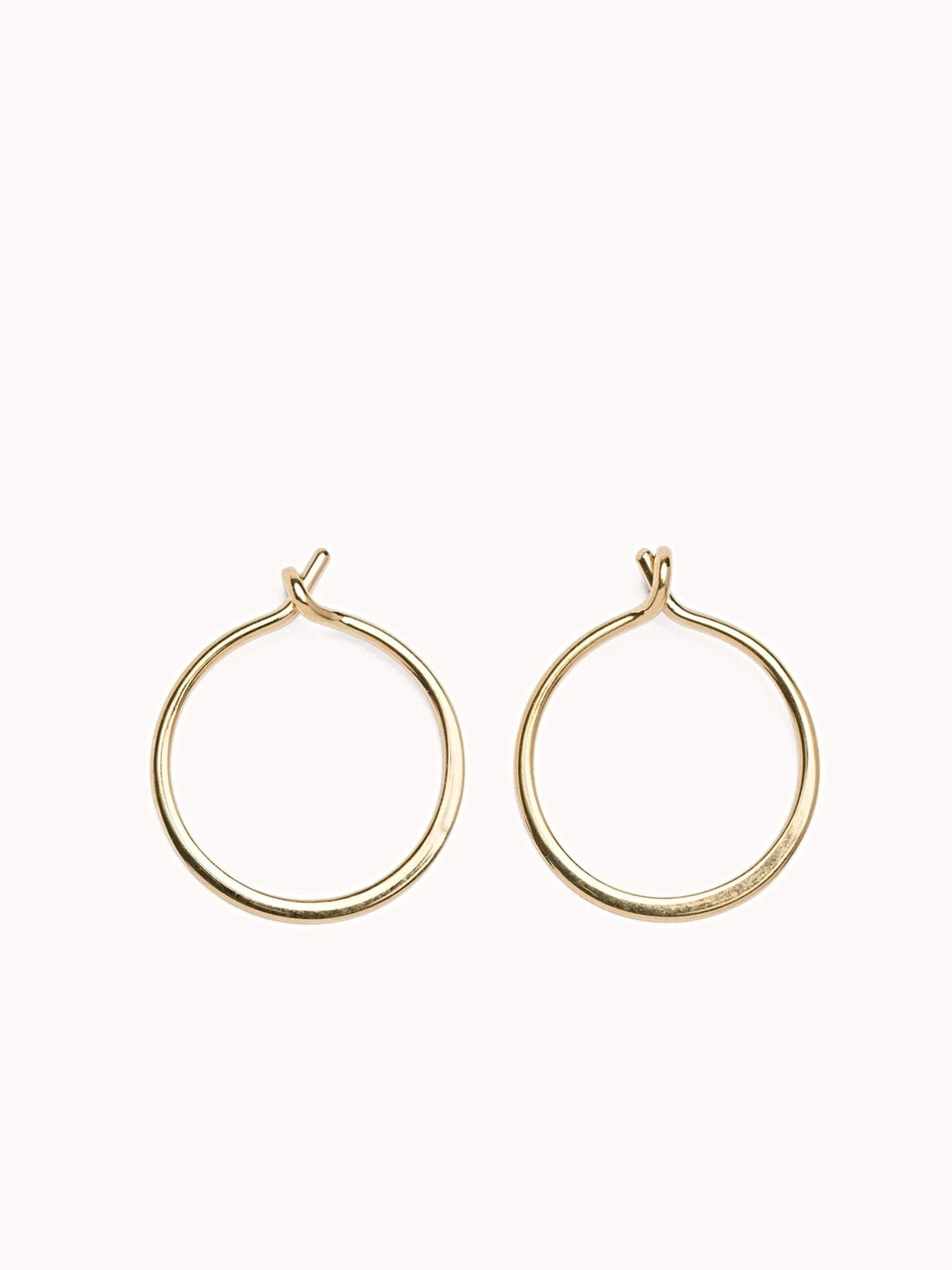 Minimalist 14K gold filled hoop earrings with a small open closure on a soft pink background