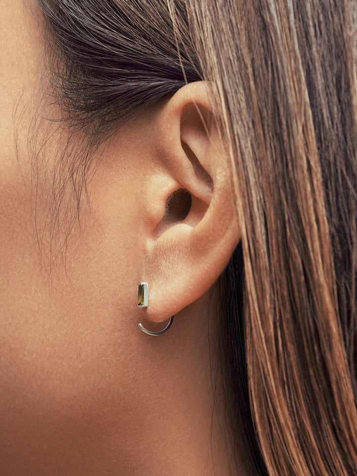 Woman wearing sterling silver peridot open hoop earrings, a timeless and sophisticated jewelry piece.