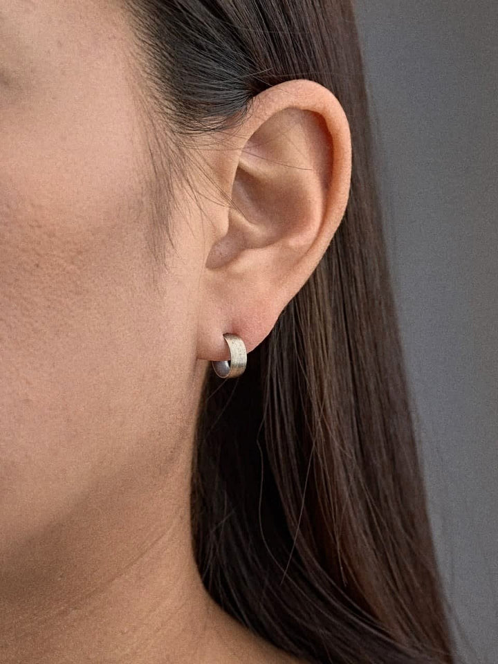 Petite sterling silver hoop earring worn on earlobe, side view of model.