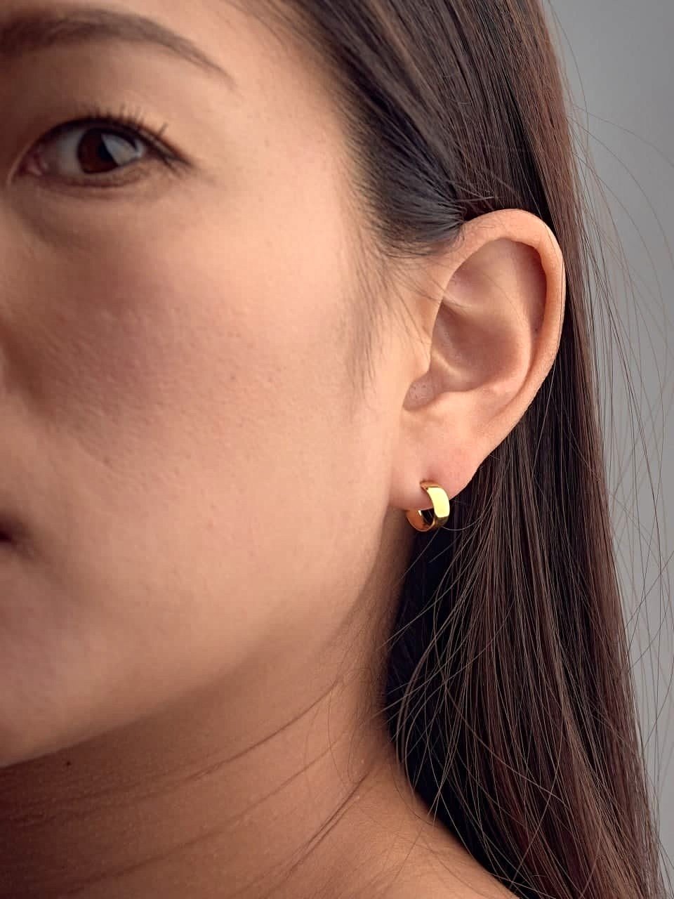Gold hoop earring worn on earlobe, side portrait of woman with long hair.