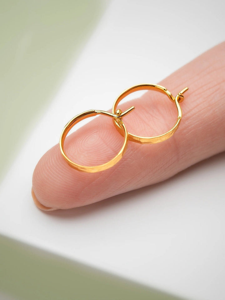 Hand holding medium hammered 24K gold matte hoop earrings – showcasing unique texture and craftsmanship