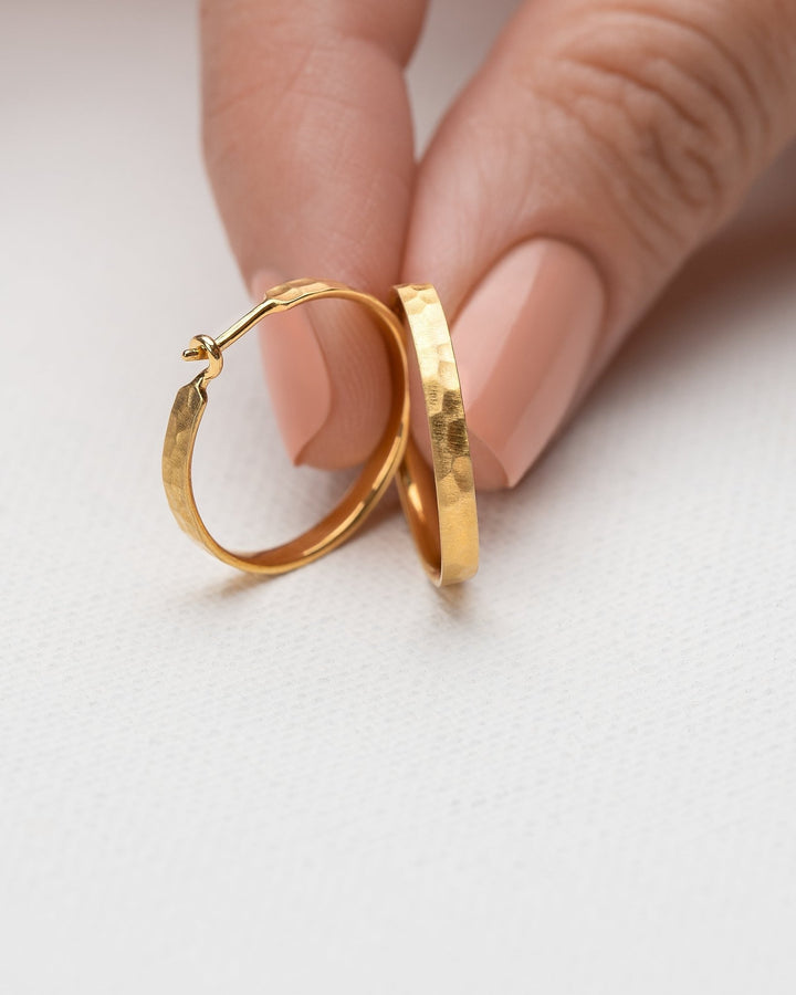 Hand holding medium hammered 24K gold matte hoop earrings – showcasing unique texture and craftsmanship