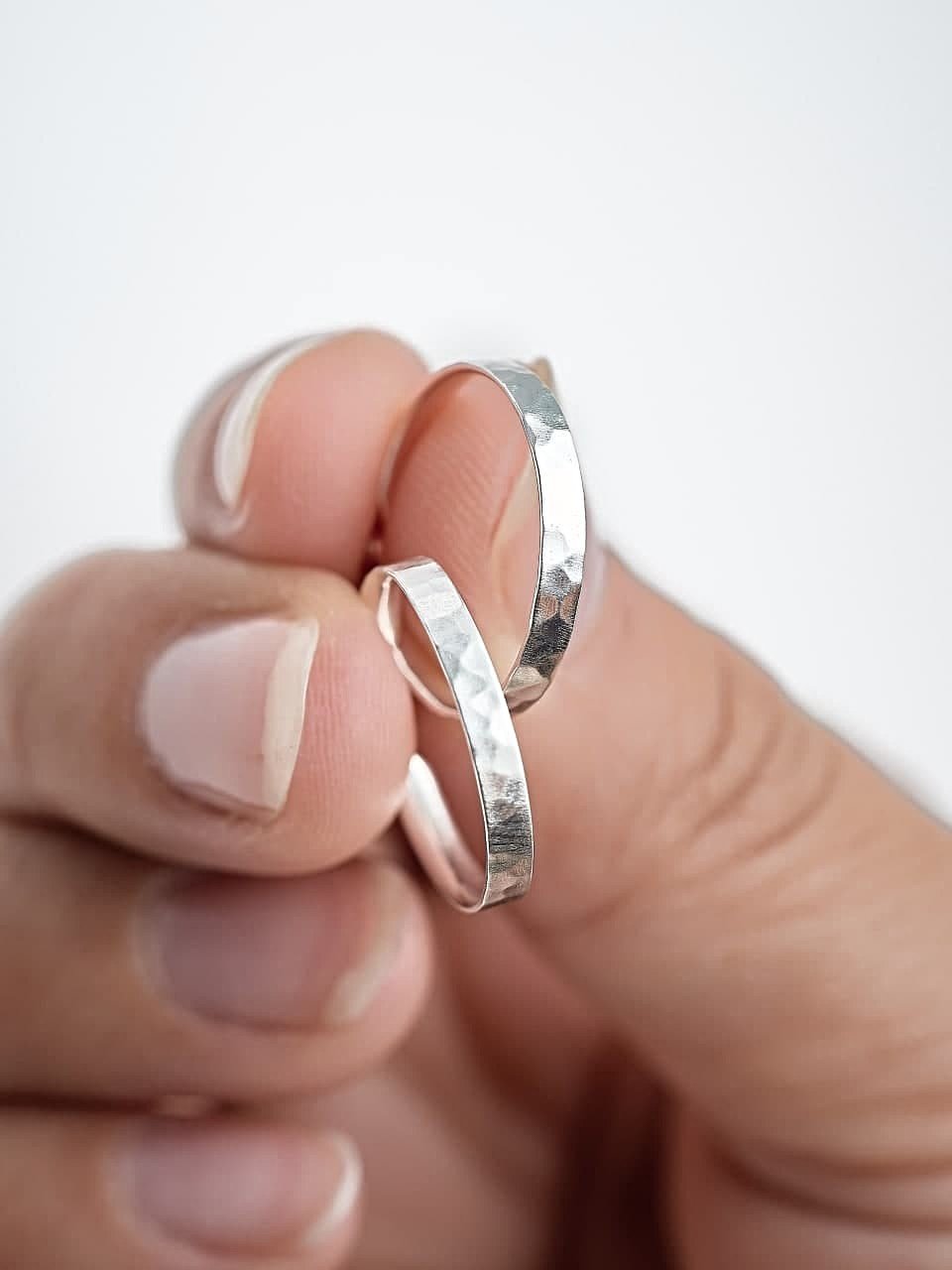 Hand holding medium hammered 925 sterling silver matte hoop earrings – elegant and eco-friendly