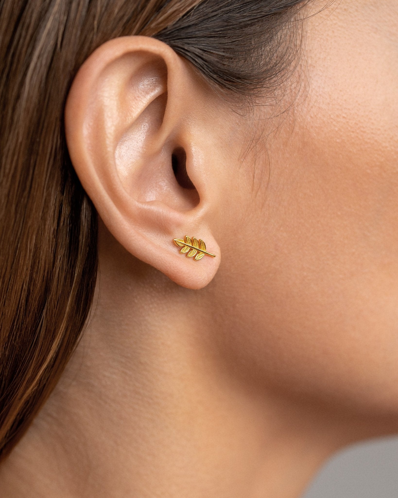 Gudrun gold leaf stud earrings worn — elegant botanical shape on ear.